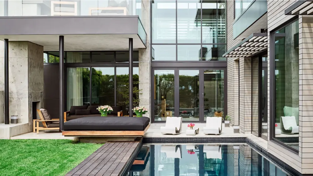 Exterior view of a modern luxury house with the infinity pool and outdoor lounge overlooking a scenic hillside landscape